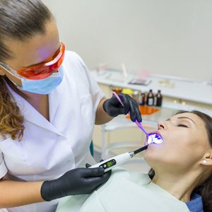 Adult female dentist treating patient woman teeth. Medicine, dentistry and healthcare concept.